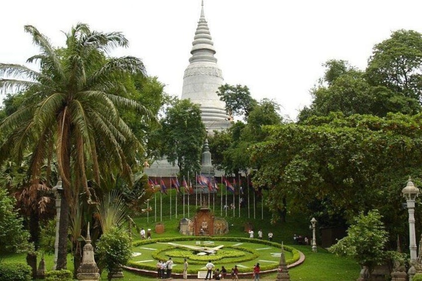 A white stupa surrounded by a well-maintained garden with palm trees and a central fountain. 4