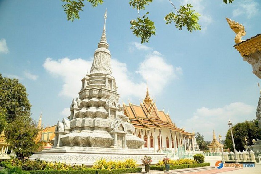A white temple with a multi-tiered stupa and a golden spire, surrounded by lush greenery and other traditional structures. 1
