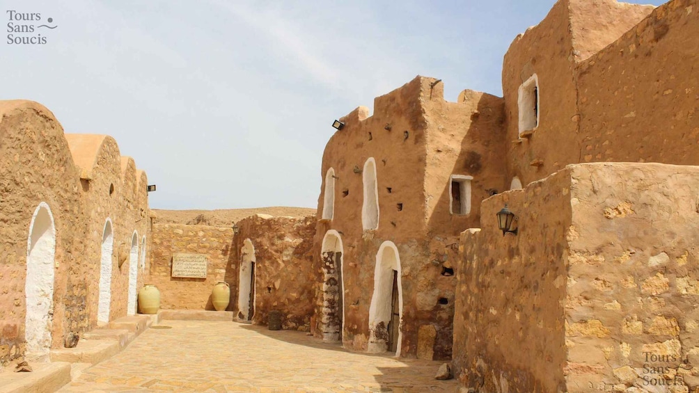 An ancient stone pathway flanked by traditional buildings with arched doorways and windows. 5