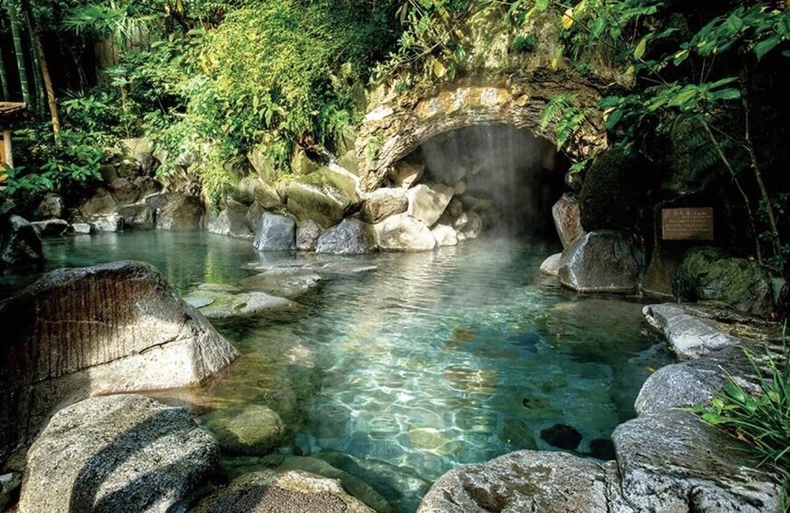 A clear stream with rocks, a stone bridge, and lush greenery. 2