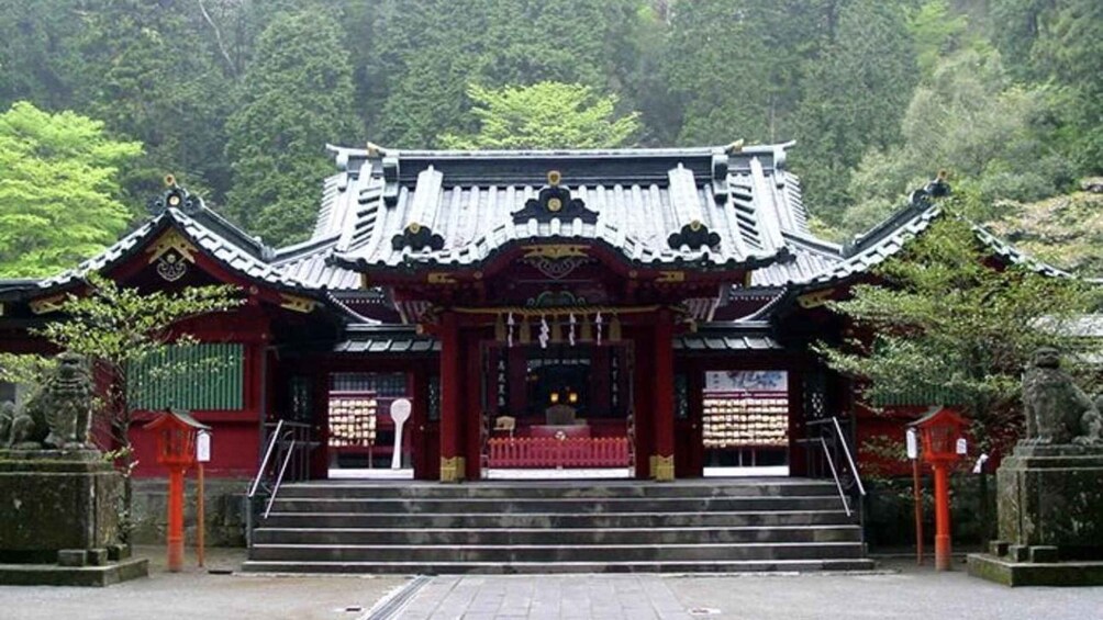 A traditional Japanese temple with a red gate, stone lanterns, and a staircase leading to the entrance. 5