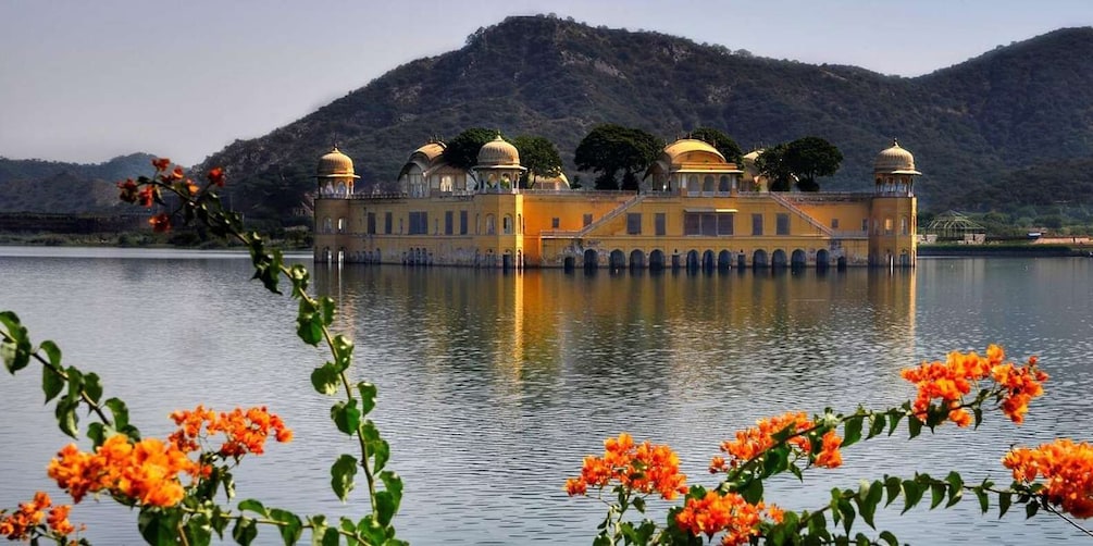A yellow building with domes on a lake, surrounded by hills. 3