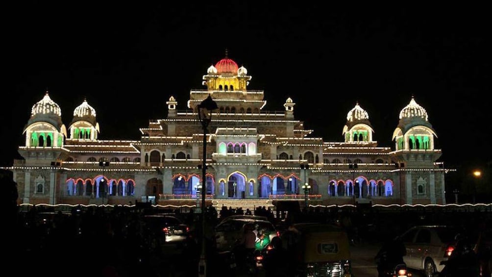 A brightly lit building with multiple domes and arches at night. 2