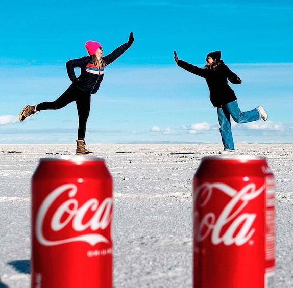 Two people dancing on a snowy field with Coca-Cola cans in the foreground. 2