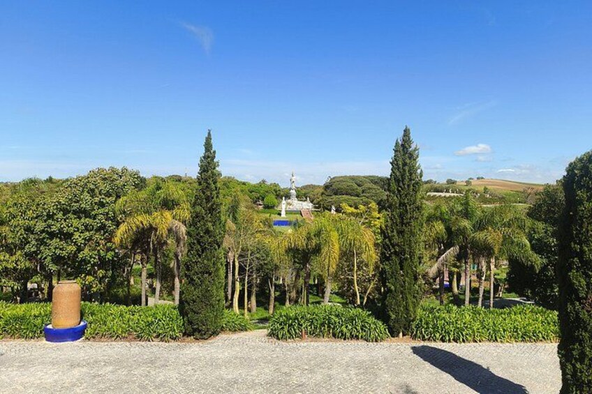 Un jardín ajardinado con una estatua, árboles y un cielo azul claro. 4