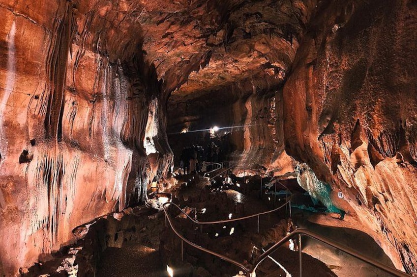 Una cueva con estalactitas y estalagmitas, barandillas metálicas e iluminación artificial. 5