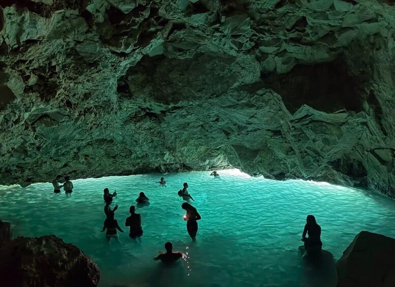 A group of people swimming in a natural pool surrounded by rocky cliffs. 1