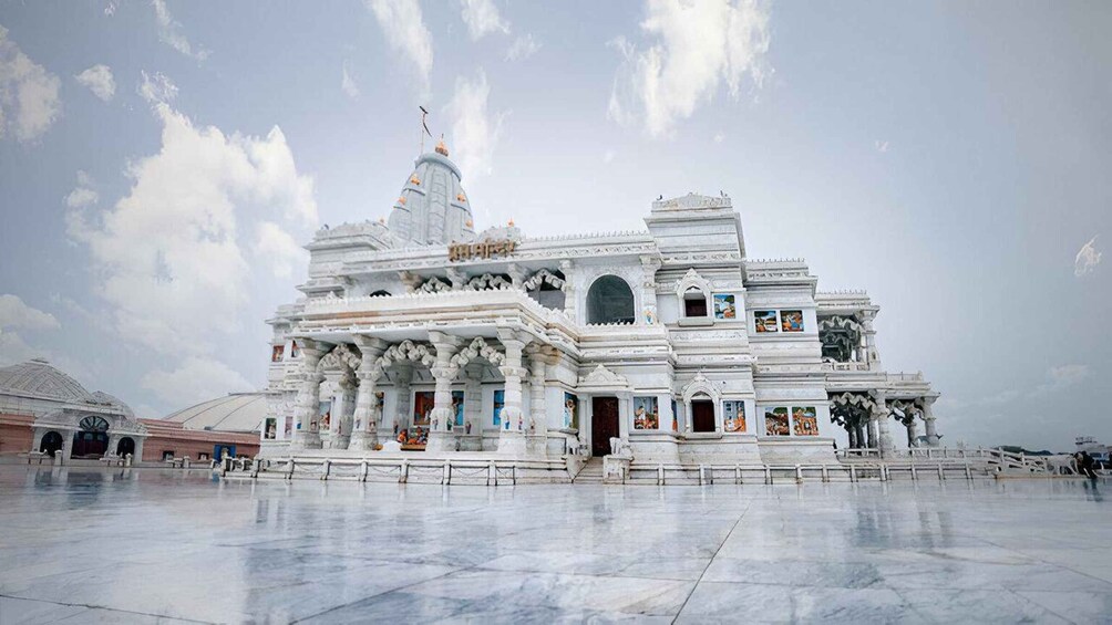 A white temple with multiple domes and intricate carvings, surrounded by a spacious courtyard. 4