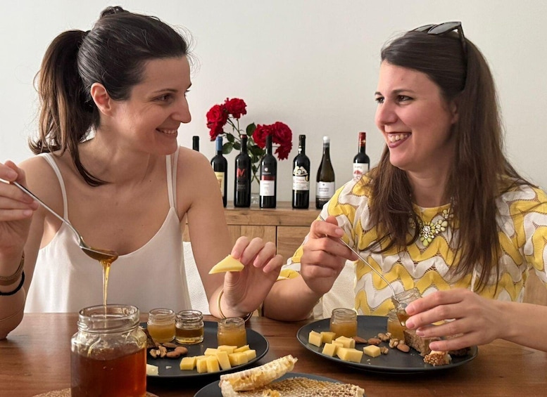 Two people tasting food at a table with cheese, nuts, and honey. 5