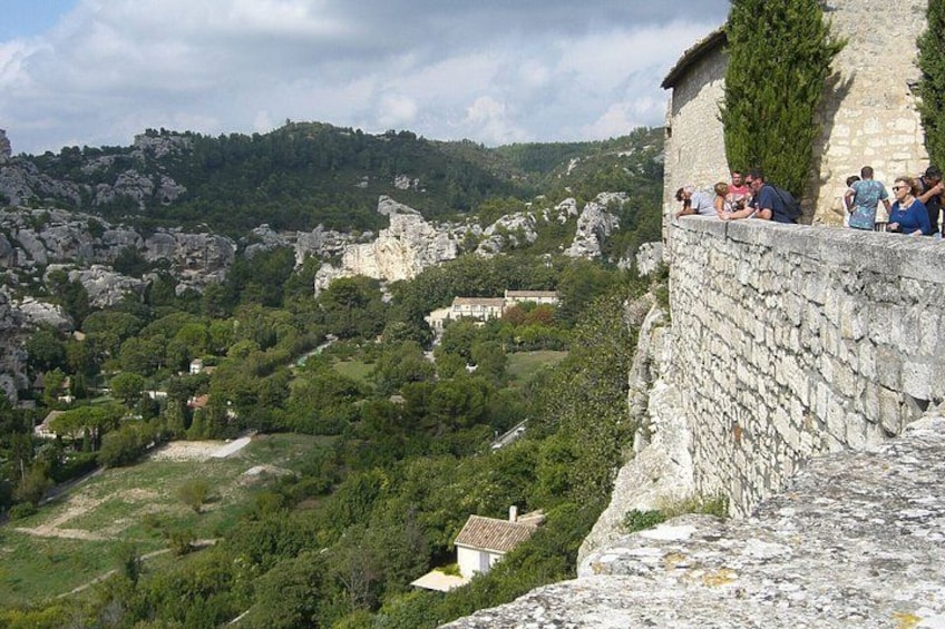 Eine Steinmauer mit Personen darauf, mit Blick auf ein Tal mit Grünflächen und Gebäuden. 2