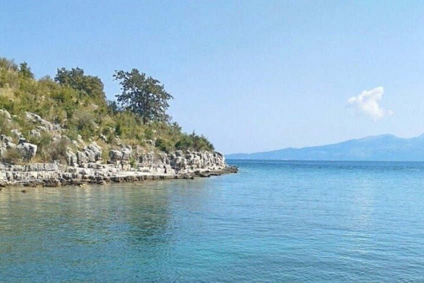 Un paysage côtier caractérisé par des falaises rocheuses, une mer calme et des montagnes à l’horizon. 2