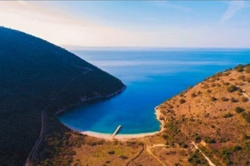 Un paysage côtier avec une mer bleue et limpide, une route sinueuse et un terrain vallonné. 4