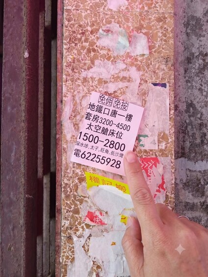 A hand holding a piece of paper with text and numbers, placed on a textured surface with a mix of colors and patterns. 5