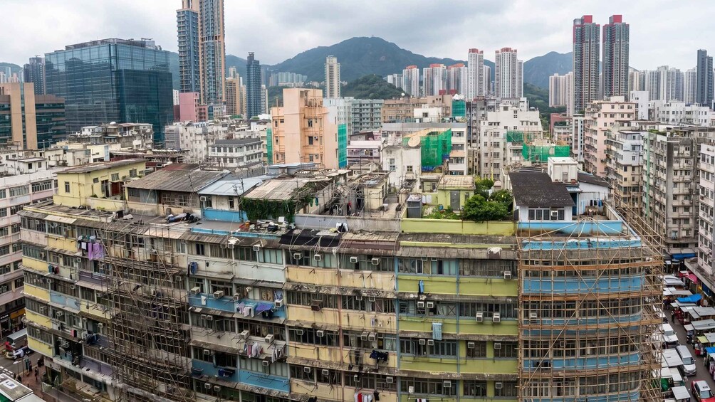 A densely packed urban area with multi-story buildings, some under construction, and a backdrop of high-rise buildings and mountains. 3