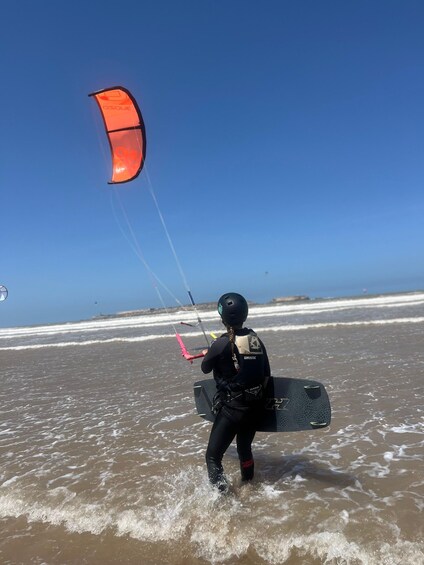 A person kiteboarding on a beach with waves. 5