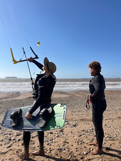 Two people on a beach with a kiteboard and a kite. 4