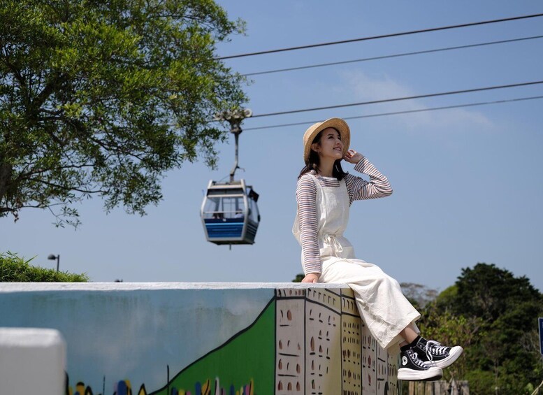A person sitting on a concrete structure with a cable car in the background. 4