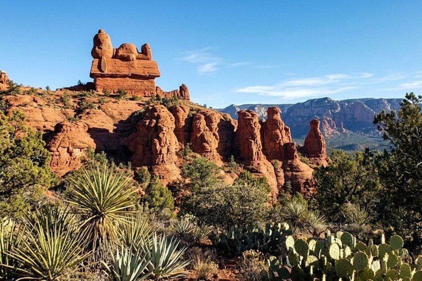 A desert landscape with red rock formations, cacti, and a clear blue sky. 2