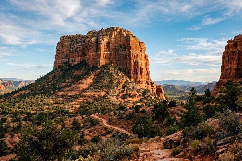 A desert landscape with prominent red rock formations, sparse vegetation, and a clear sky. 3