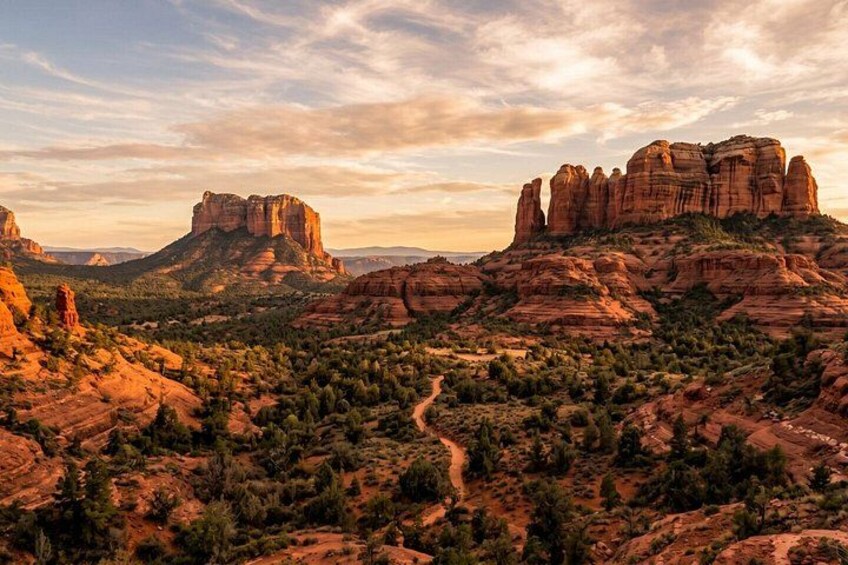 A desert landscape with prominent red rock formations and a winding dirt road. 2