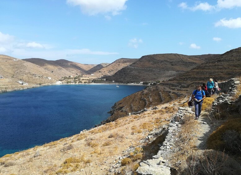 A coastal hiking trail with rocky terrain and a view of a calm sea. 4
