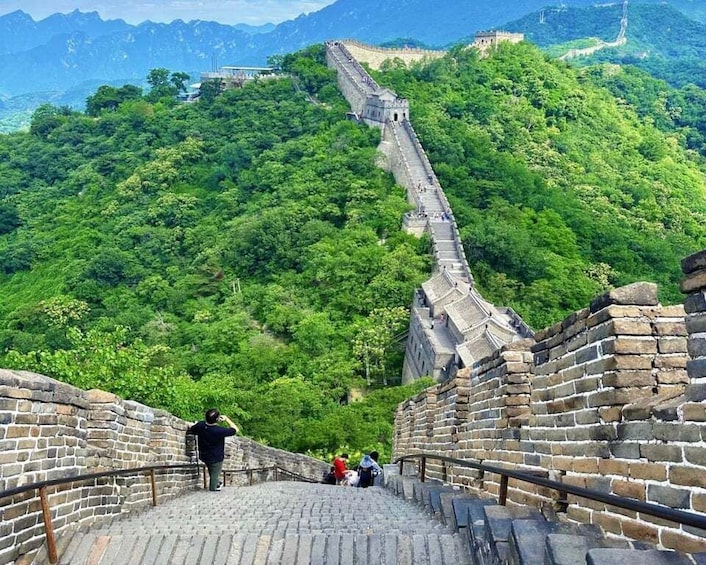 The Great Wall of China winding through lush green mountains. 1