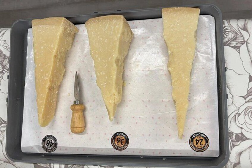 A cheese cutting board with three wedges of cheese and a cheese knife. 5
