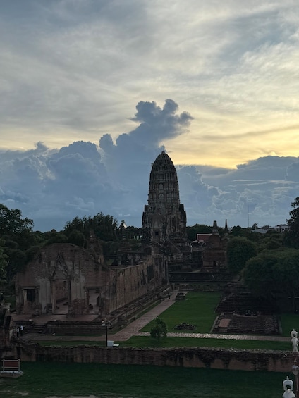 An ancient temple complex with a prominent central tower, surrounded by ruins and greenery. 1