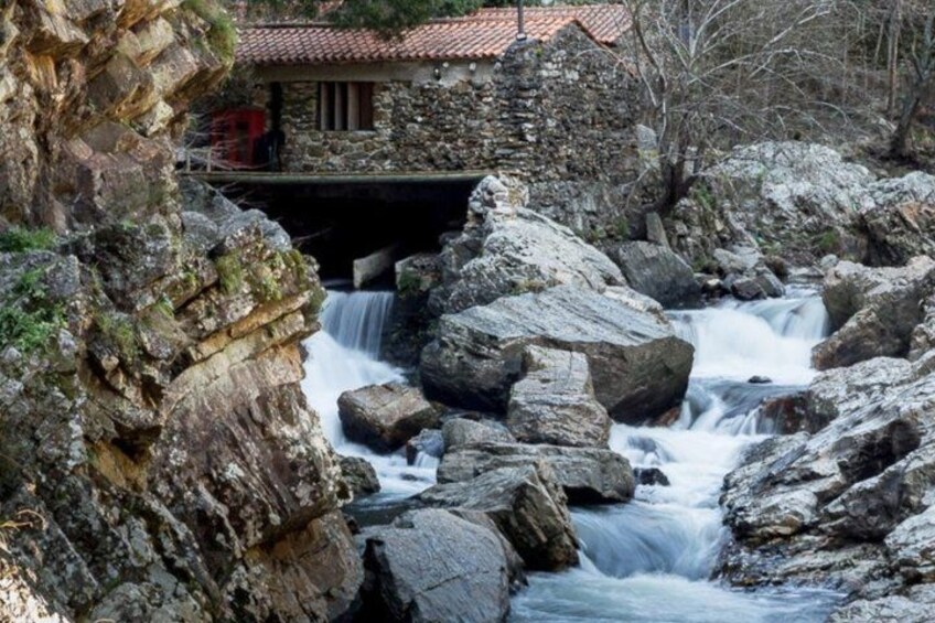 Un arroyo pedregoso con una casa de piedra y un puente. 2