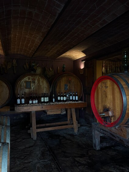 A cellar with wooden barrels and bottles of wine. 2