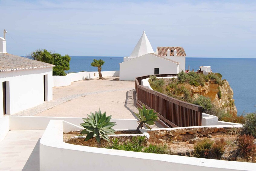 A coastal building with a white facade, a conical roof, and a view of the sea. 5