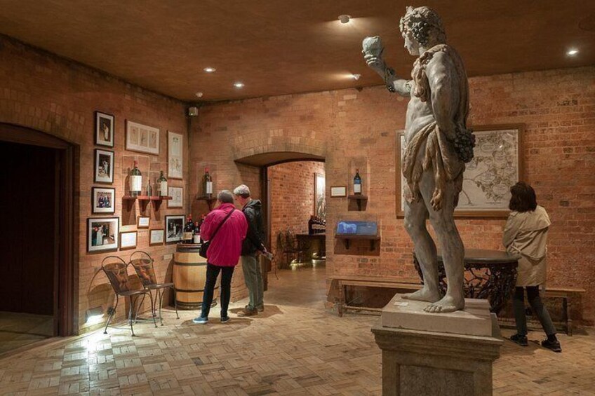 A museum interior with a classical statue, brick walls, and visitors. 4