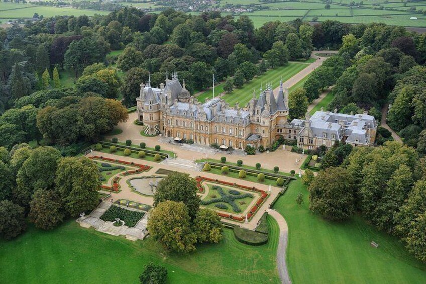 A large, historic castle surrounded by lush gardens and green fields. 5