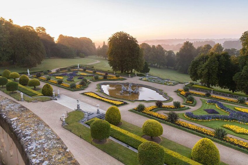 Un jardín formal con parterres de flores geométricos, un estanque central y setos cuidadosamente recortados. 4