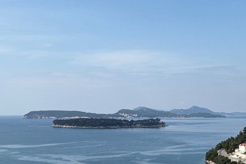 Un paisaje costero con una isla grande, una isla más pequeña a lo lejos y un cielo despejado. 5