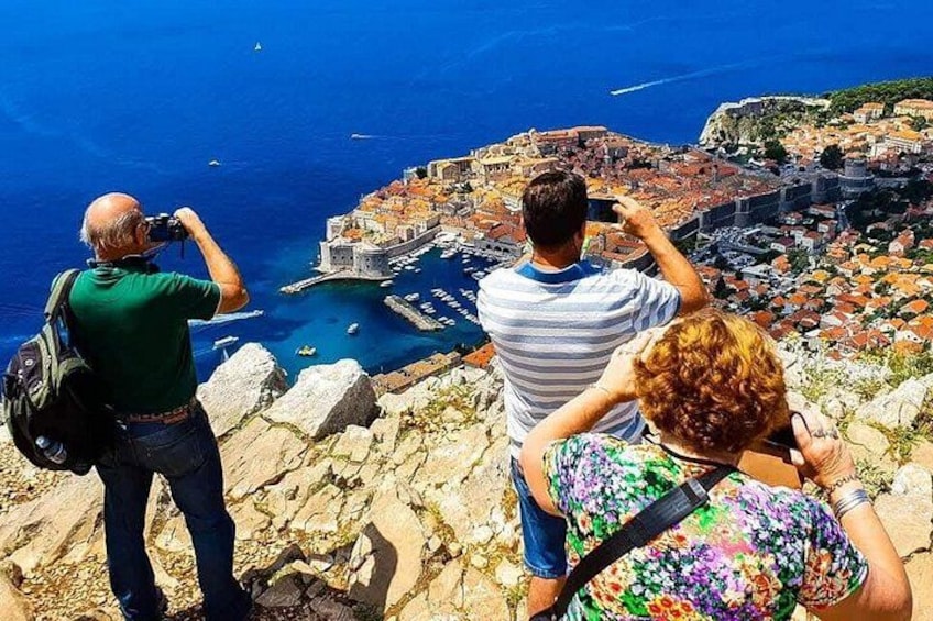 Tres personas tomando fotografías de un pueblo costero con un puerto histórico. 1