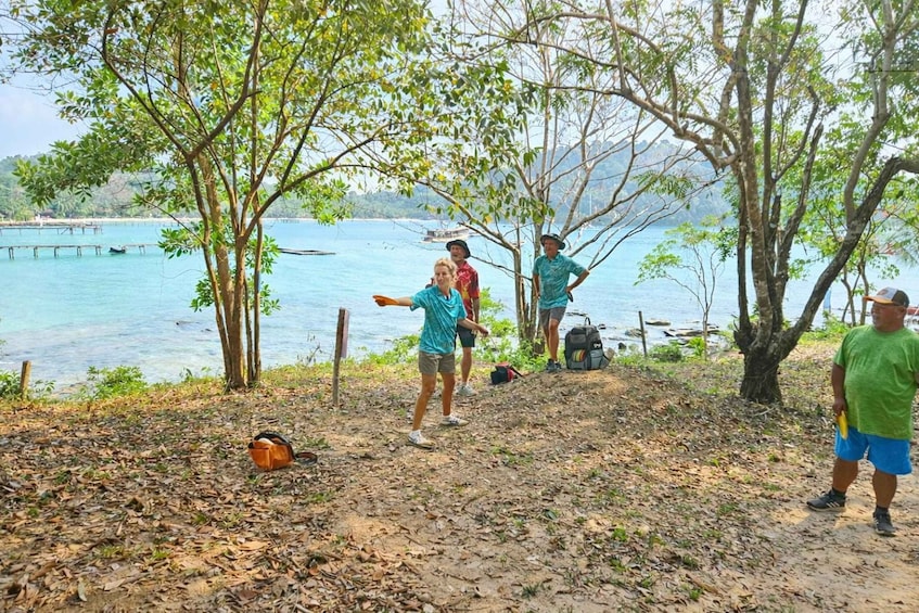 A group of people by a lake with trees and a dock in the background. 1