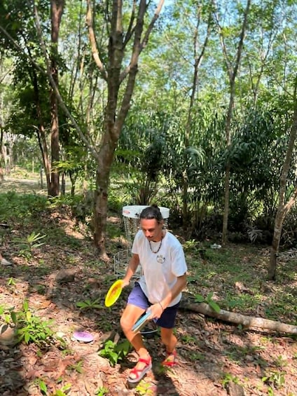 A person in a forest holding a yellow frisbee. 3