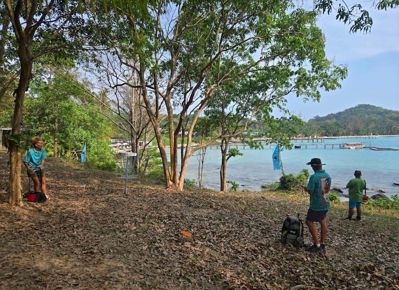 A beach with people, trees, and a boat in the water. 5