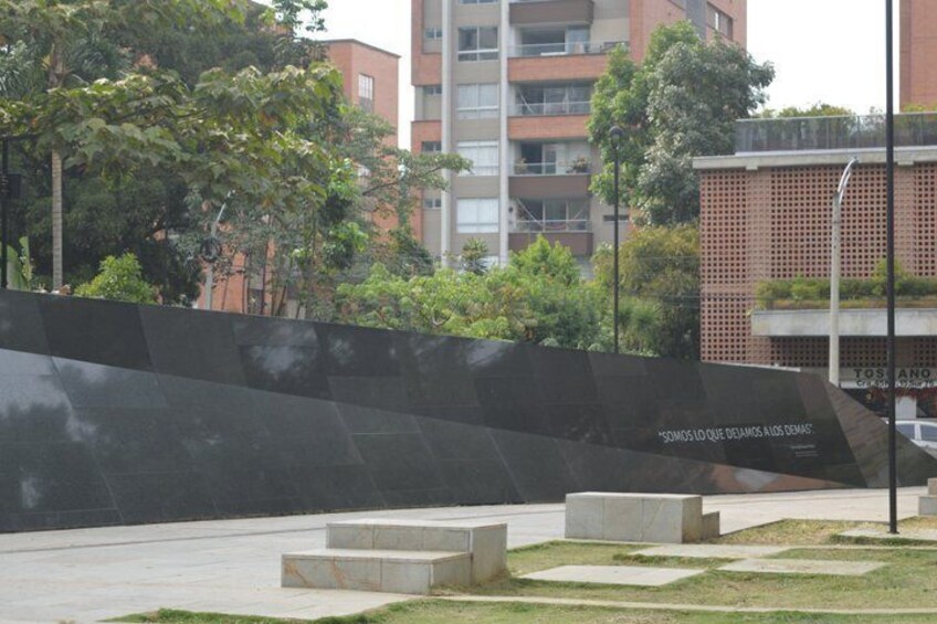 Un parque urbano moderno con un muro negro, escalones y un edificio al fondo. 4