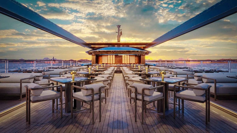 A deck with tables and chairs, a central bar, and a sunset view. 4