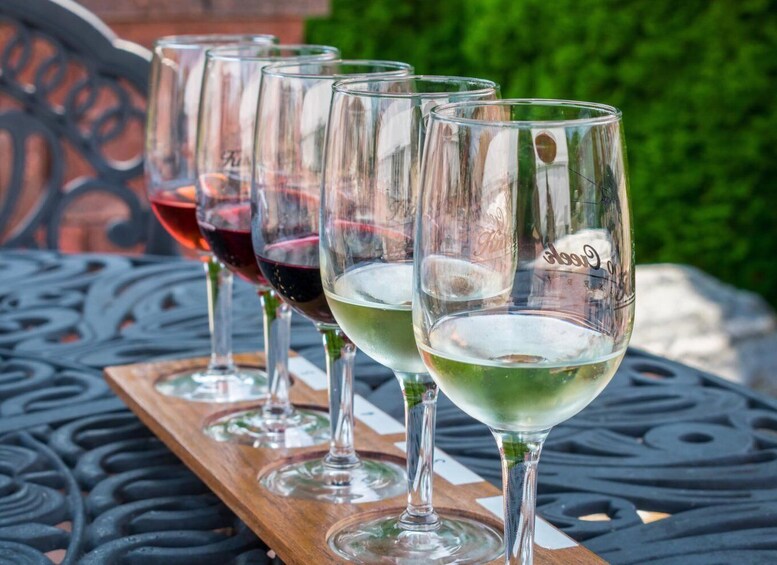 Four wine glasses on a wooden tray with a metal table. 2