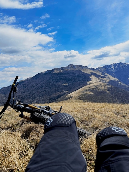 A mountain bike resting on a grassy hill with a view of a mountain range under a blue sky. 3