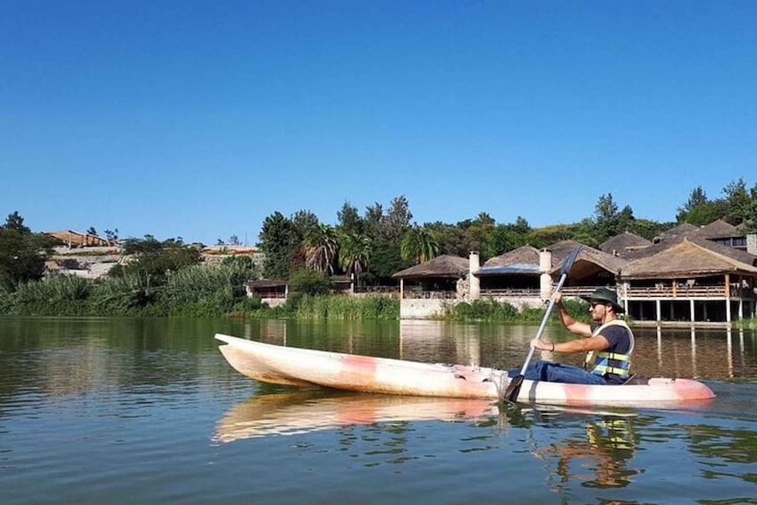 A person in a kayak on a calm body of water with houses and greenery in the background. 2