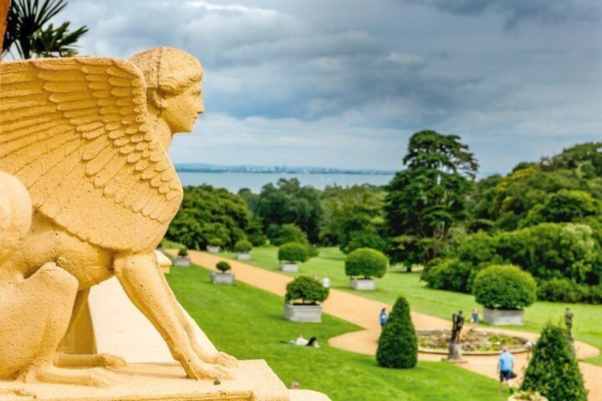 A sphinx statue overlooking a park with manicured lawns and a distant bridge. 2