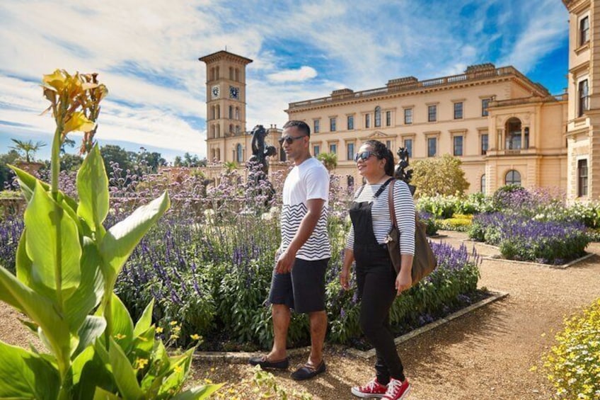 A couple standing in a garden with a historic building in the background. 5