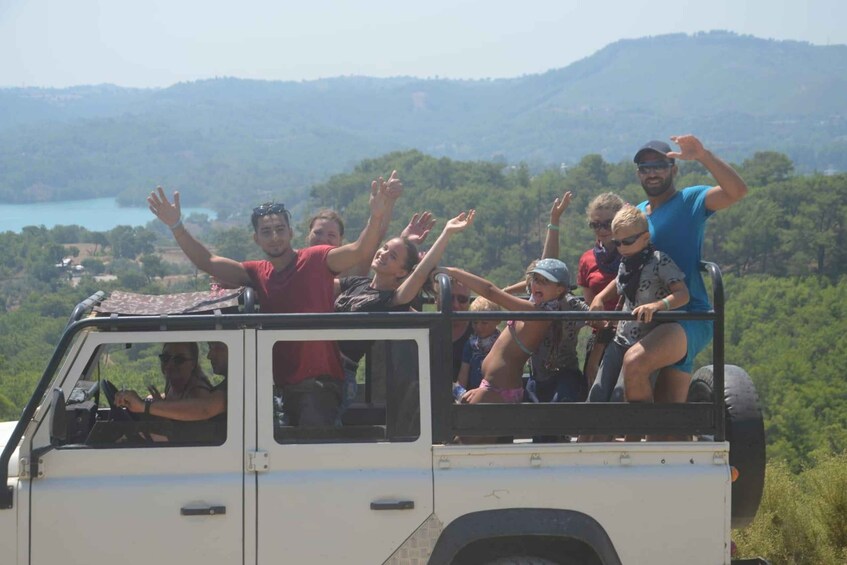 A group of people on a white off-road vehicle with a scenic landscape in the background. 2