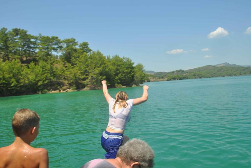 A person jumping into a turquoise lake surrounded by trees and hills. 5