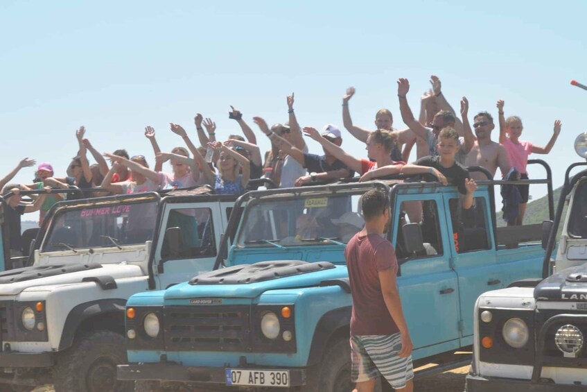 A group of people on a blue Land Rover with raised hands, likely enjoying a tour or event. 1