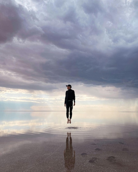 A person jumping on a reflective water surface with a cloudy sky in the background. 2